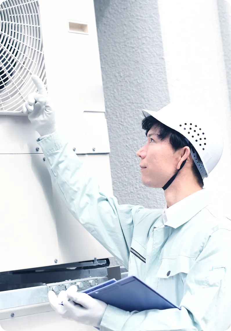 ビルの室外機をチェックする男性の写真